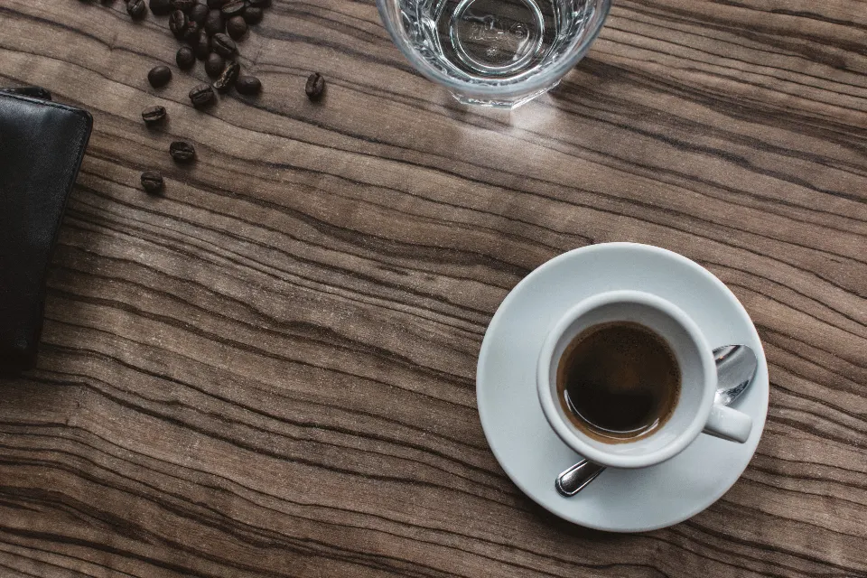 Xícara de café espresso sobre uma mesa de madeira, com grãos de café ao lado
